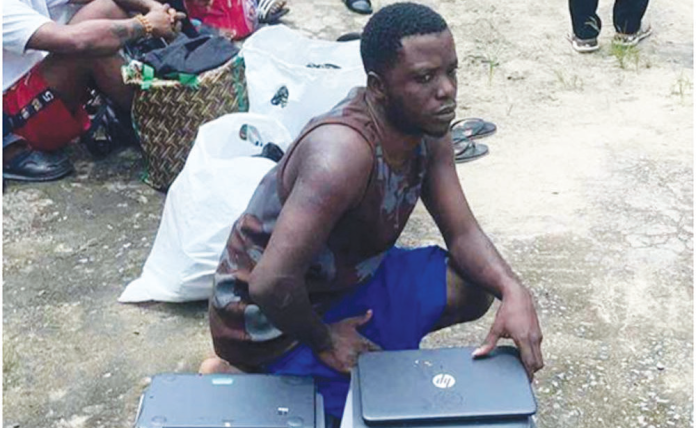 Suspected internet fraudsters posing with recovered laptops following arrest by Troops of the Headquarters 63 Brigade Nigerian Army and Sector 1 Joint Task Force, Operation Delta Safe (OPDS) in Warri, Delta State.